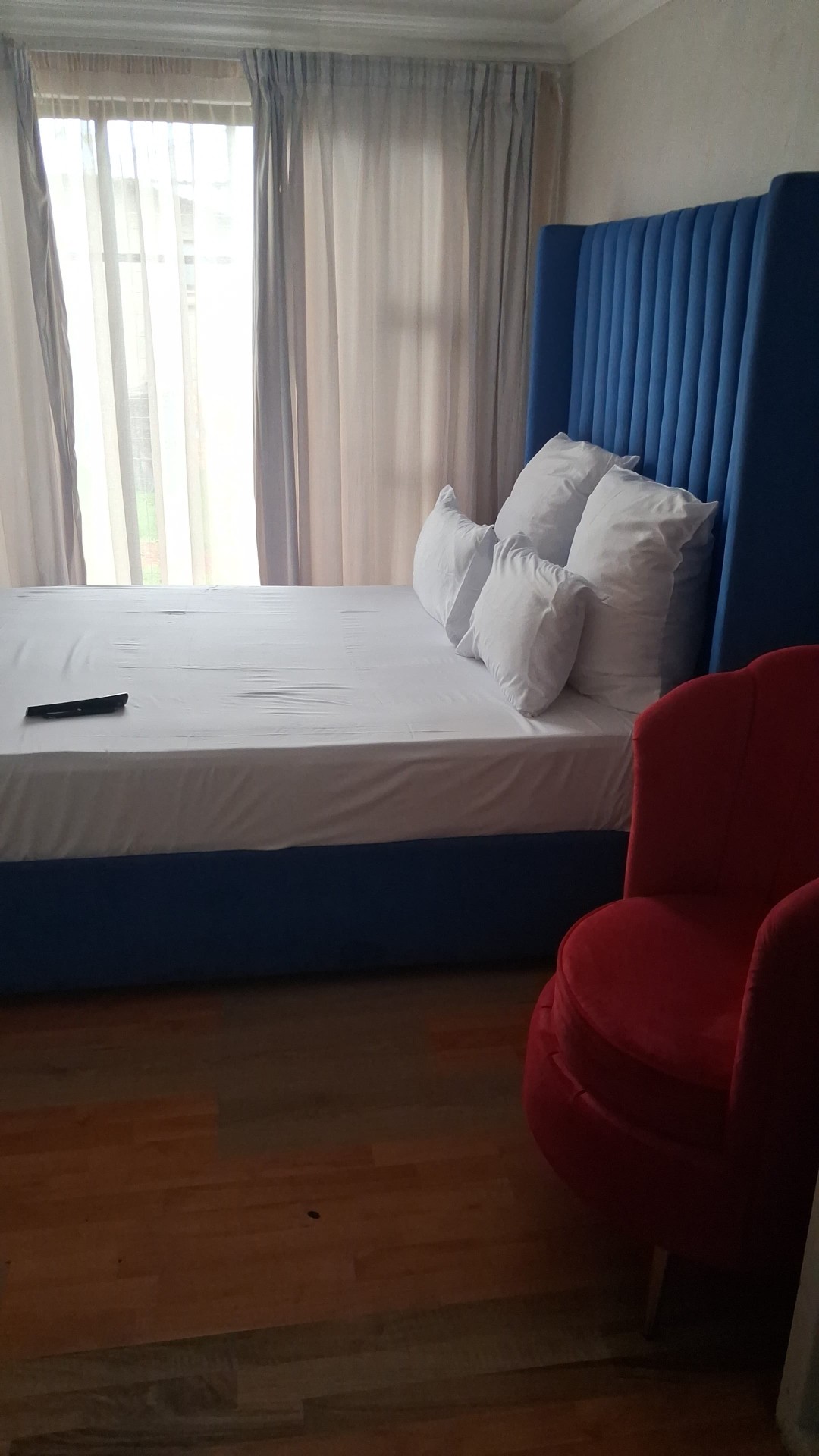 Blue tufted headboard bedroom with red accent chair