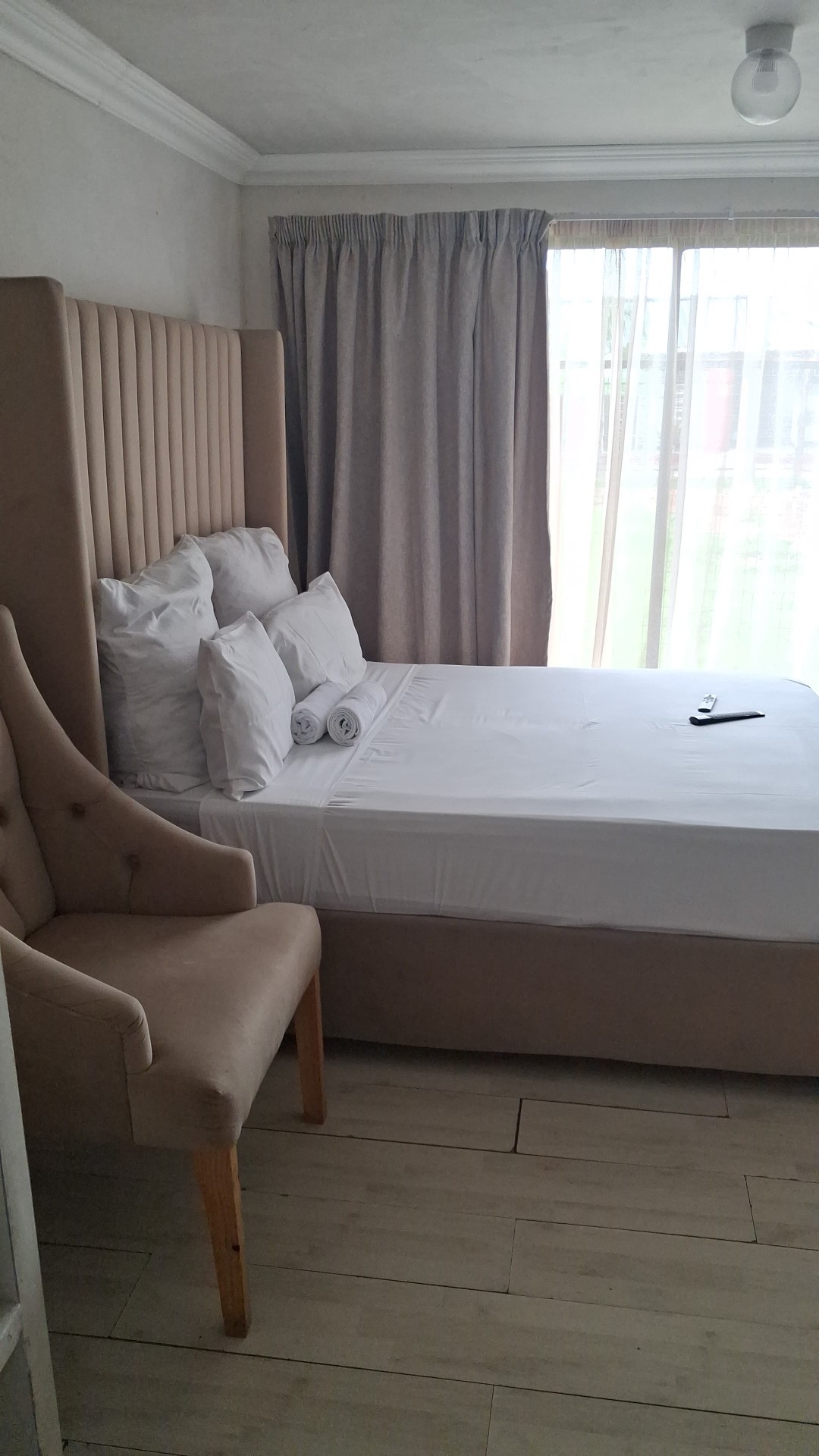Beige vertical channel headboard bedroom with wooden floor