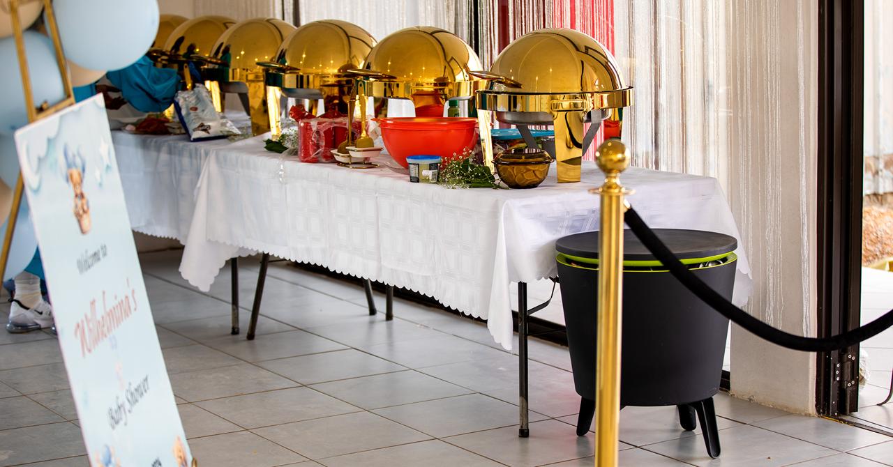 Long buffet table with six gold chafing dishes at a baby shower