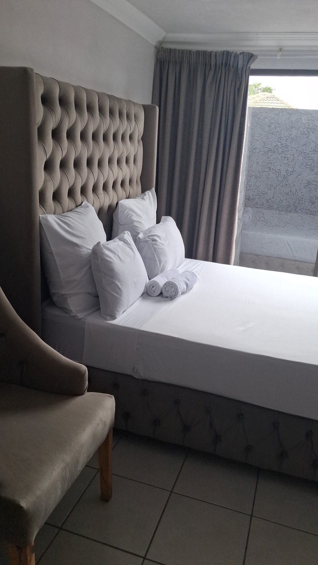 Grey tufted headboard bedroom with tiled floor