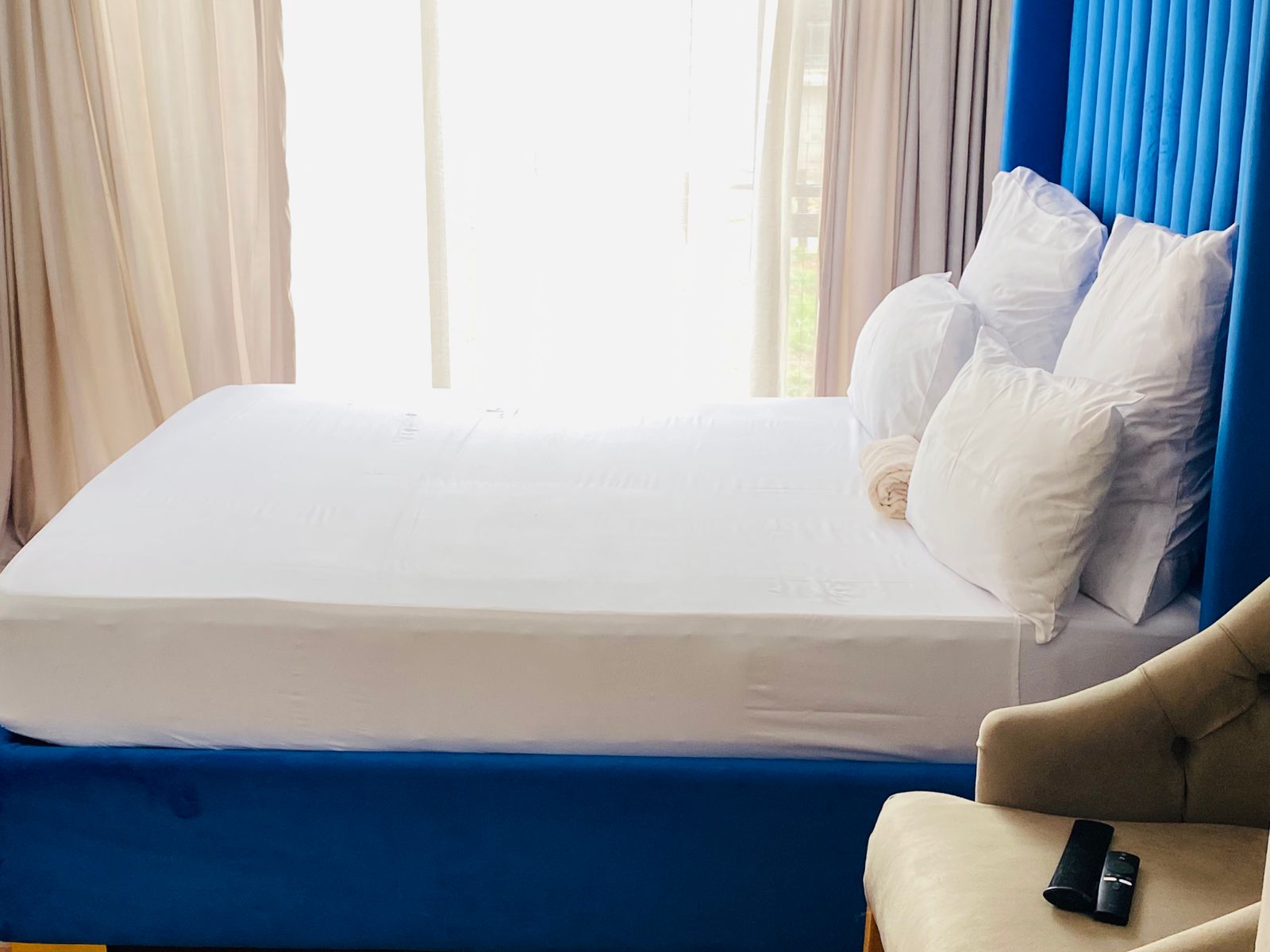 Blue upholstered bed with crisp white linen and morning light