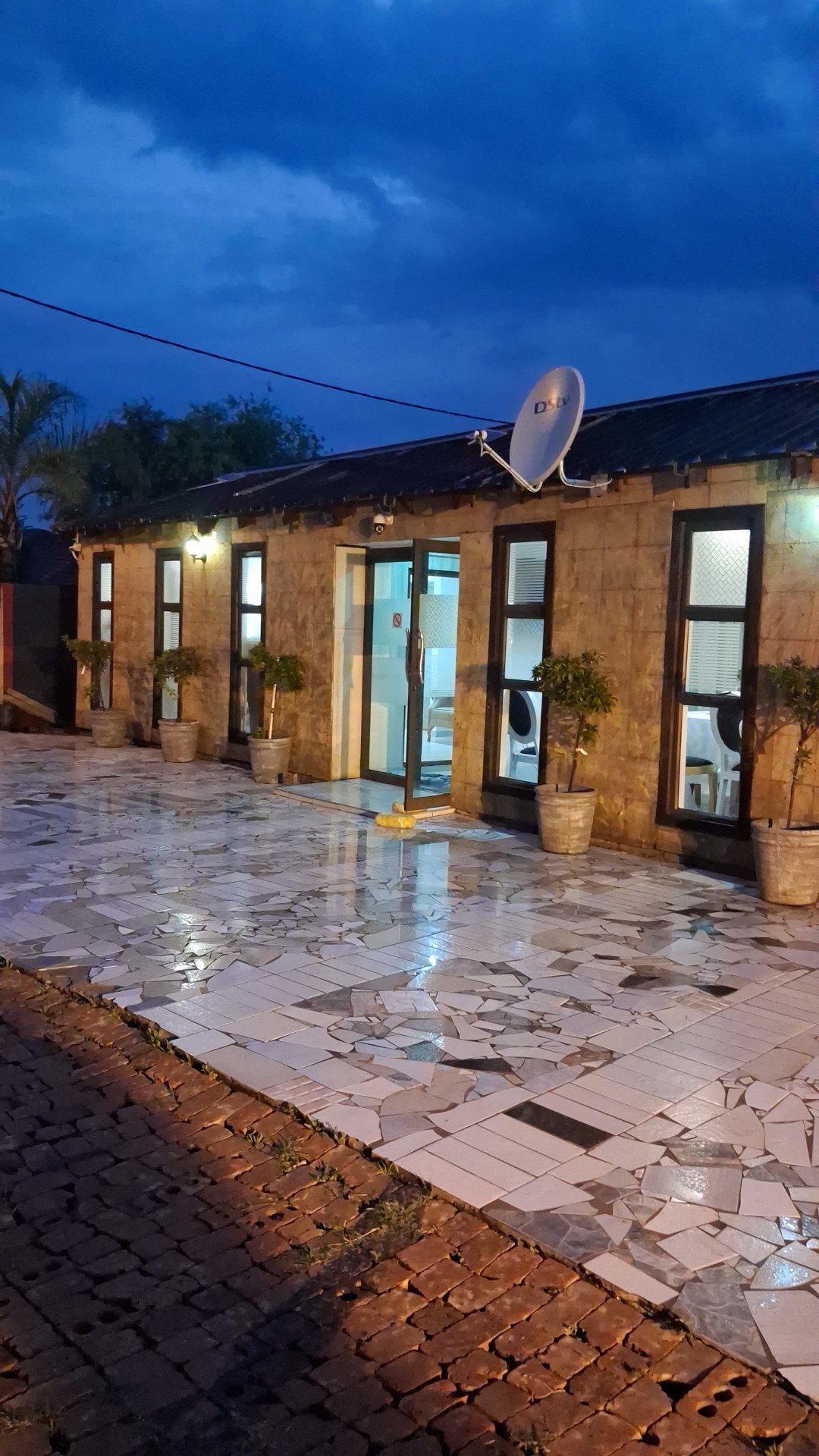 Rooms exterior at dusk with lit windows and mosaic patio