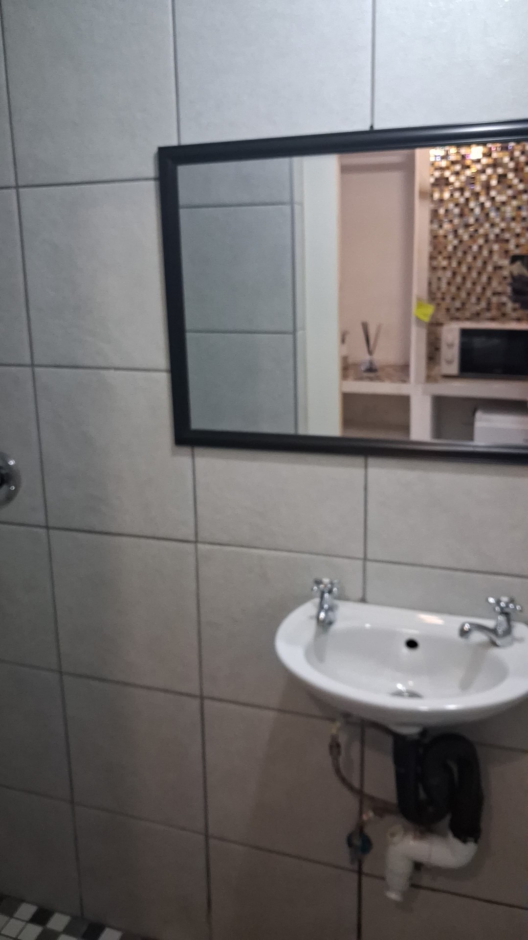 Bathroom sink with framed mirror and mosaic feature wall