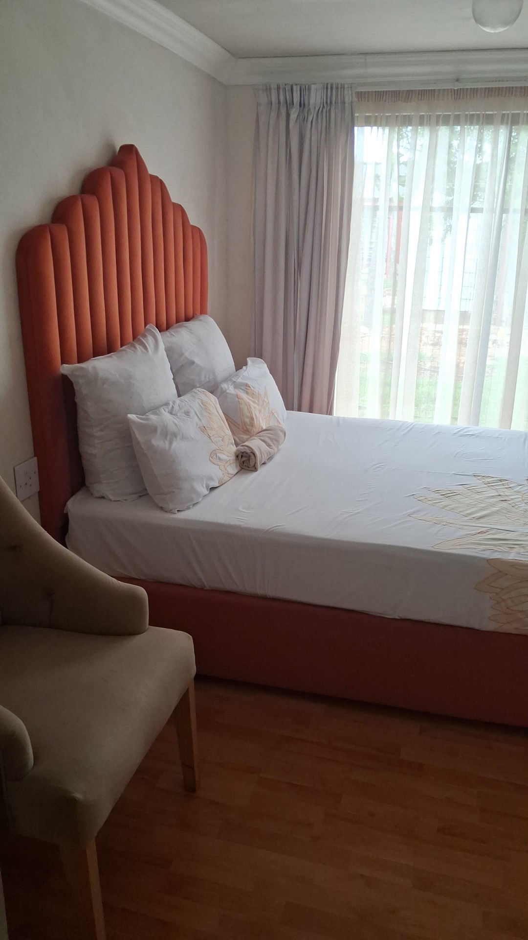 Orange scalloped headboard bedroom with wooden floor