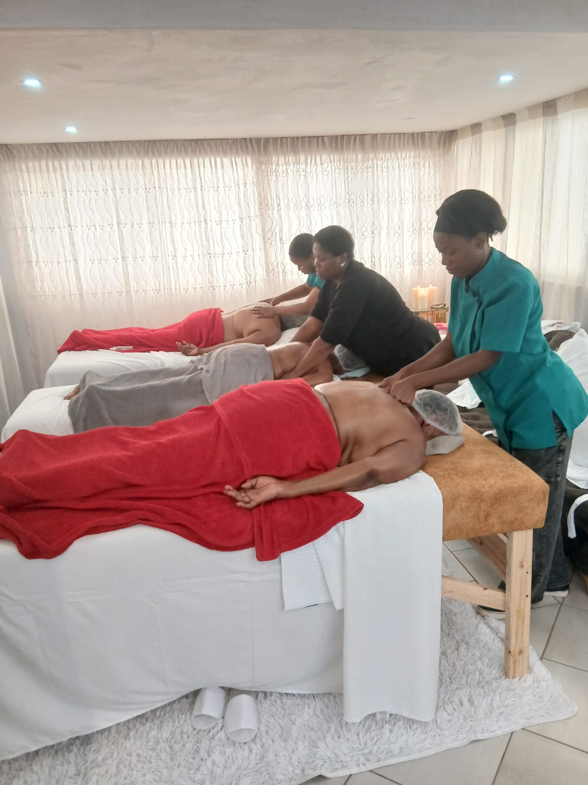 Group spa room with three beds and therapists at work