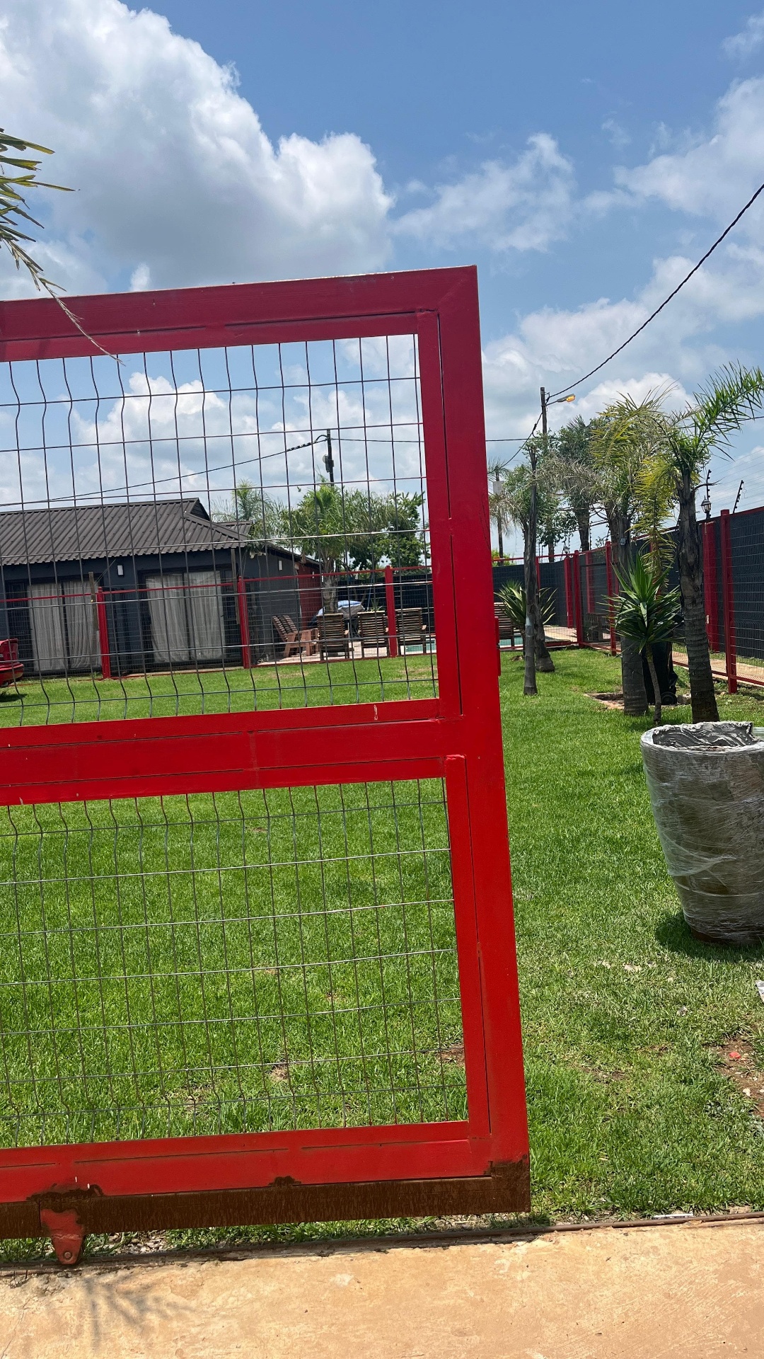 Red steel gate opening onto grounds