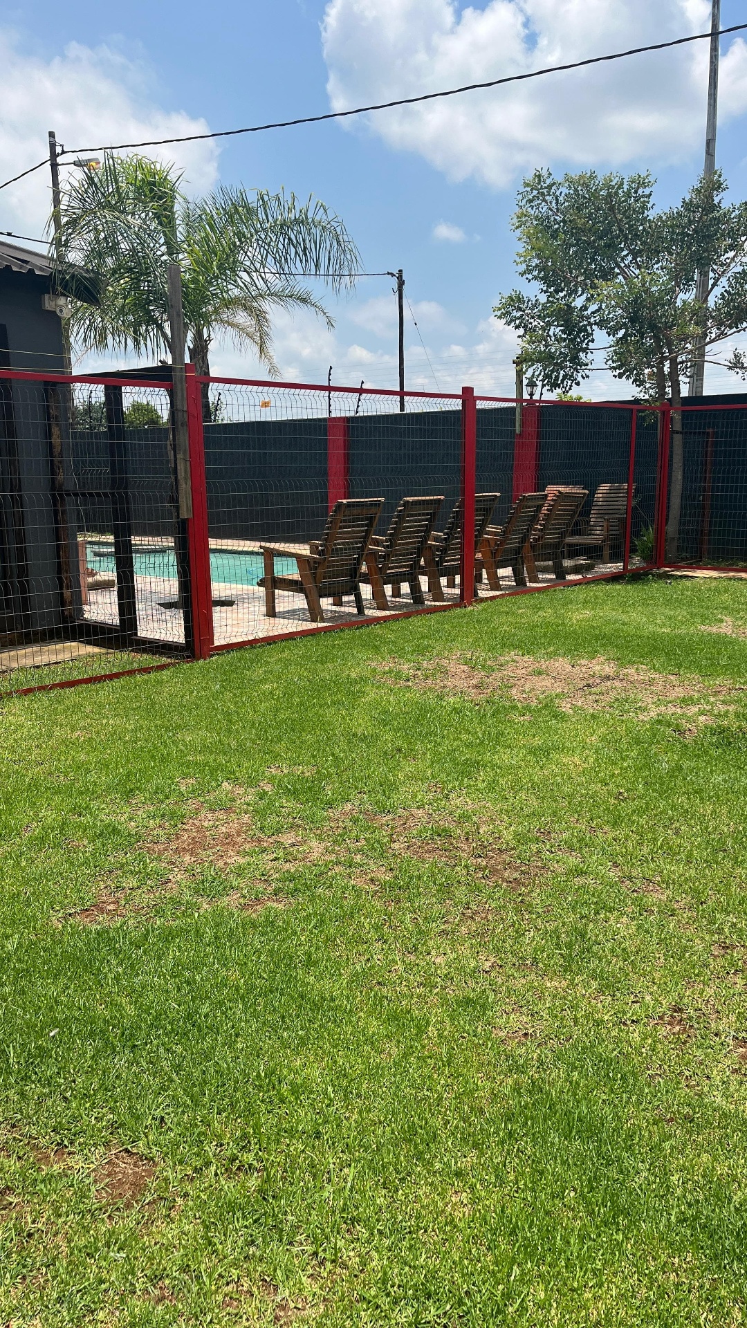 Wooden loungers behind red pool safety fence