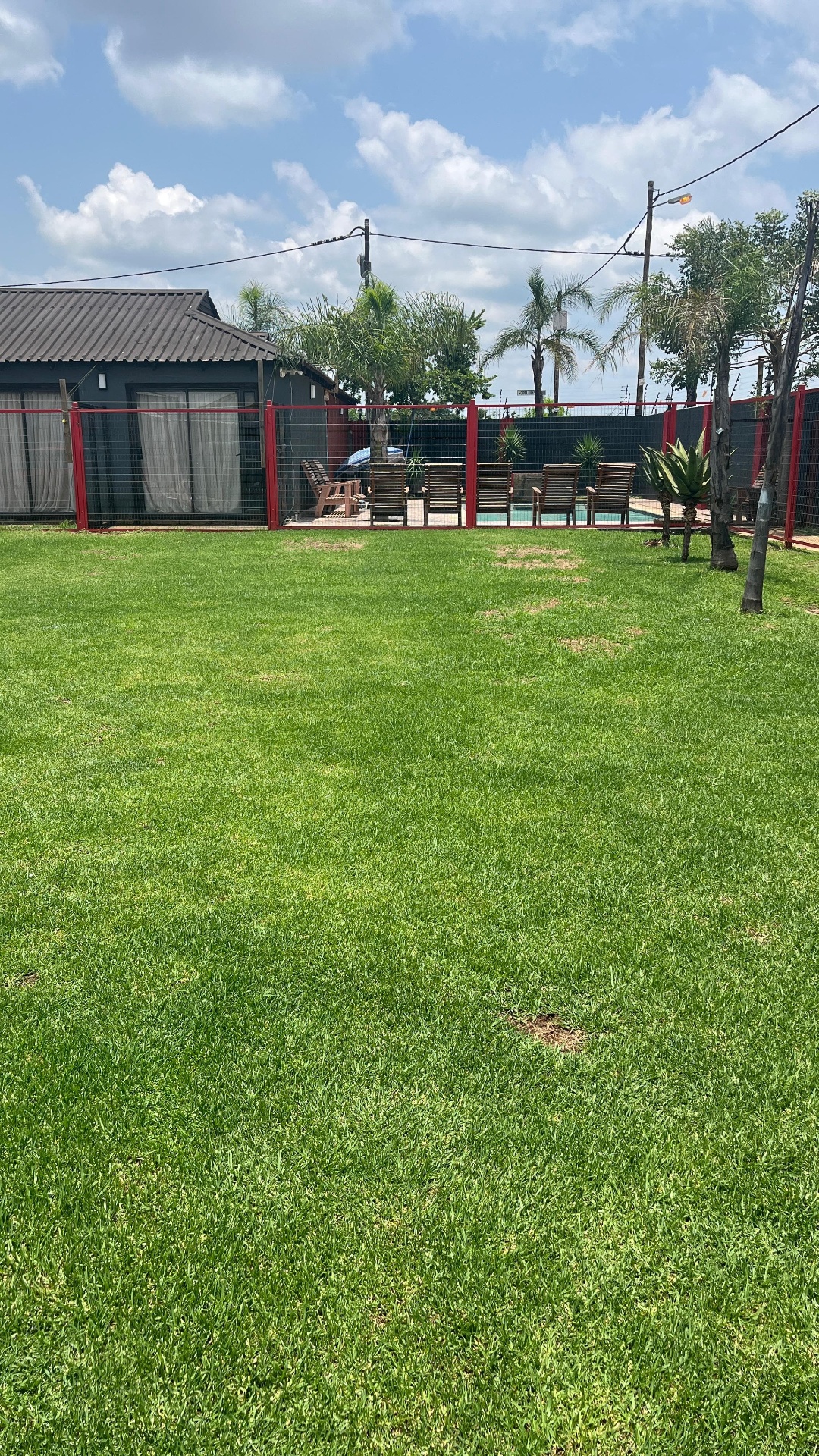 Green lawn with pool and cottage in background