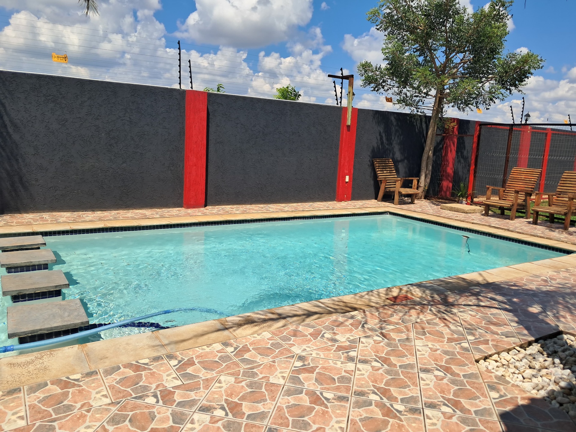 Swimming pool with red-accented feature wall and loungers