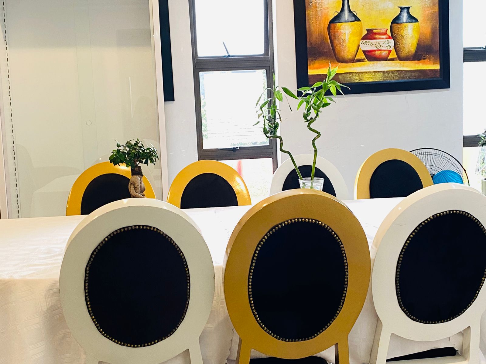 Dining room with yellow, white and black chairs and framed art