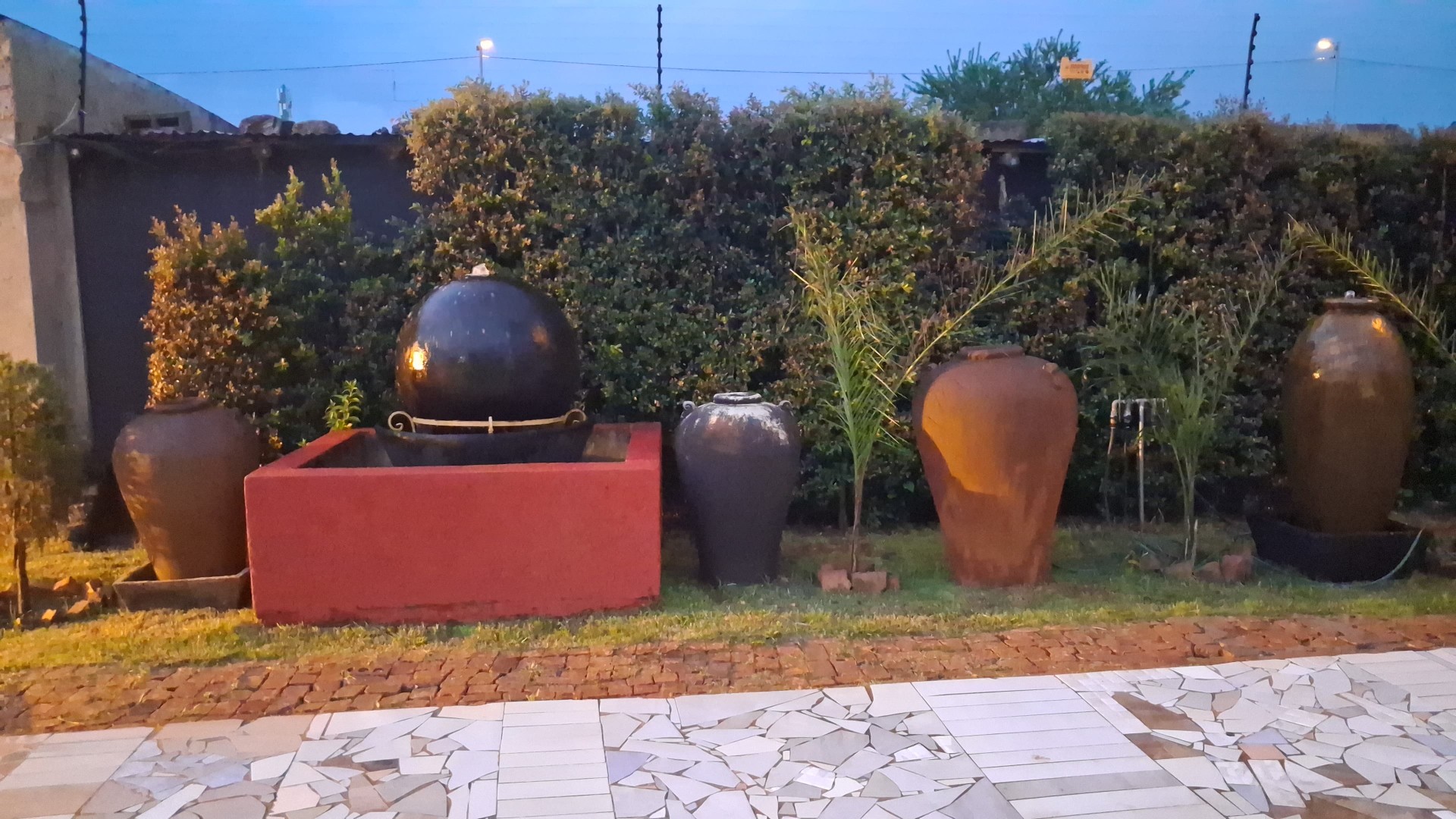 Garden with red fountain, clay pots and mosaic patio